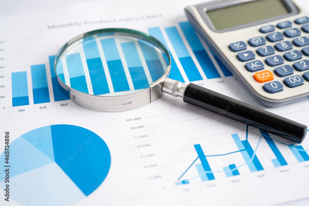 Magnifying glass and calculator on charts graphs paper. Financial development, Banking Account, Statistics, Investment Analytic research data economy, Stock exchange trading, Business office concept.