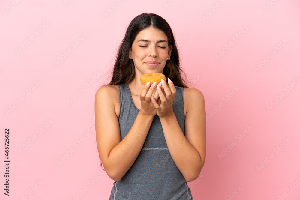 Young caucasian woman isolated on pink background holding a donut Young caucasian woman isolated on pink background holding a donut