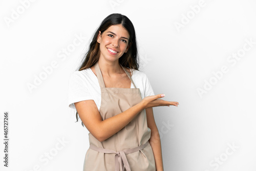 Restaurant waiter over isolated white background presenting an idea while looking smiling towards photo