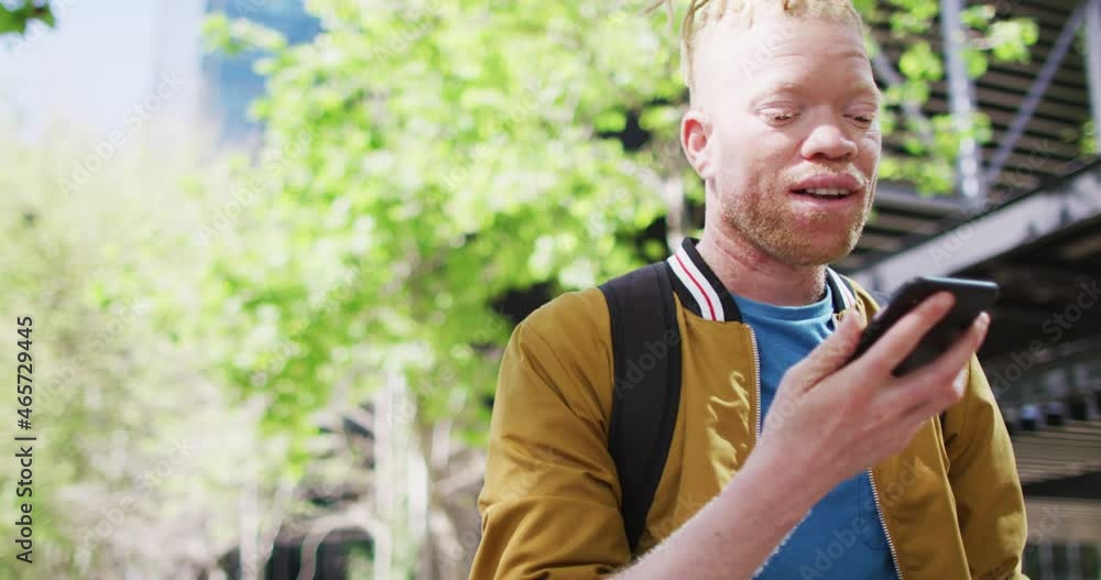 Happy albino african american man with dreadlocks in park talking on smartphone Happy albino african american man with dreadlocks in park talking on smartphone