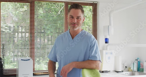 Portrait of smiling caucasian male dentist looking at camera at modern dental clinic photo