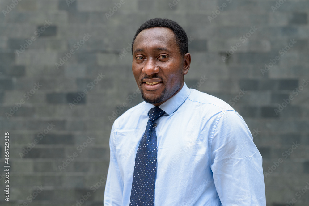 Portrait of handsome African businessman in city smiling Portrait of handsome African businessman in city smiling
