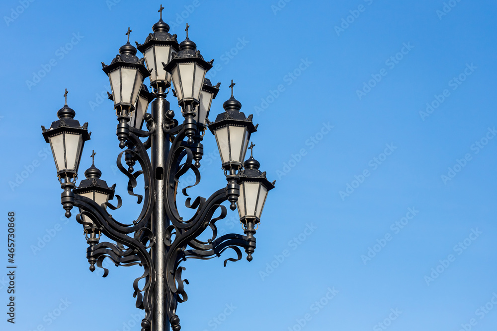 Beautiful vintage lamp post with swirls and curls against sky. Decoration of streets and parks. Illumination of streets in cities and towns
