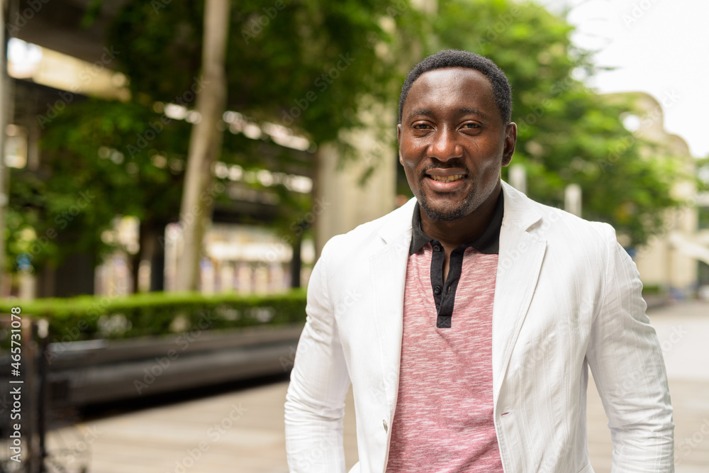 Fototapeta premium Portrait of handsome African businessman in city smiling