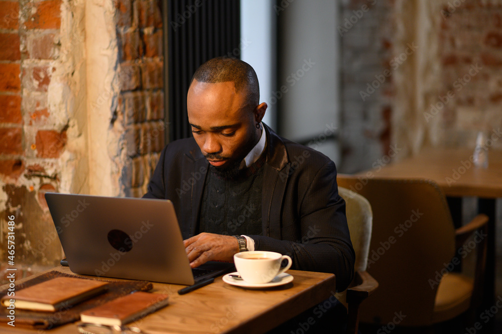 An African American student works at a laptop in a cafe An African American student works at a laptop in a cafe