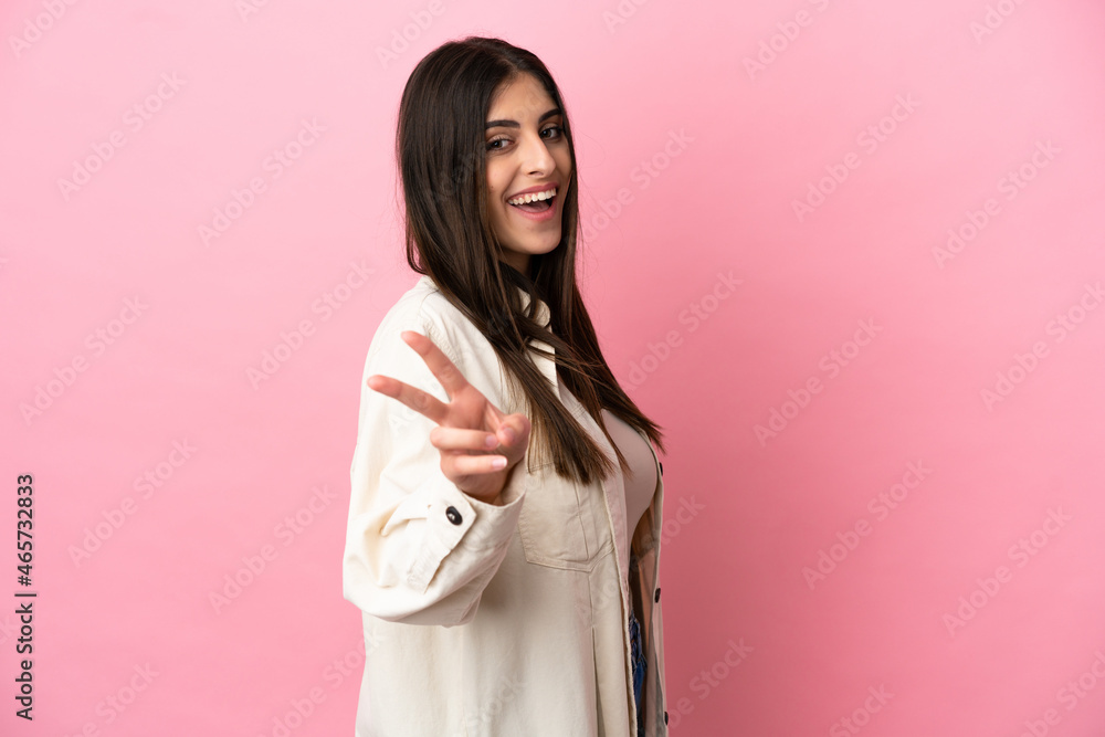 Young caucasian woman isolated on pink background smiling and showing victory sign Young caucasian woman isolated on pink background smiling and showing victory sign