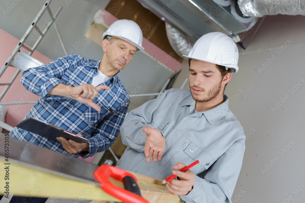 two carpenters are analyzing construction measurements two carpenters are analyzing construction measurements