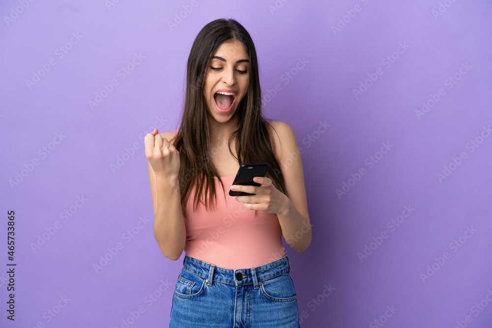 Young caucasian woman isolated on purple background surprised and sending a message Young caucasian woman isolated on purple background surprised and sending a message