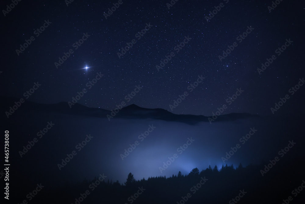 Beautiful view of misty mountains under starry sky at night