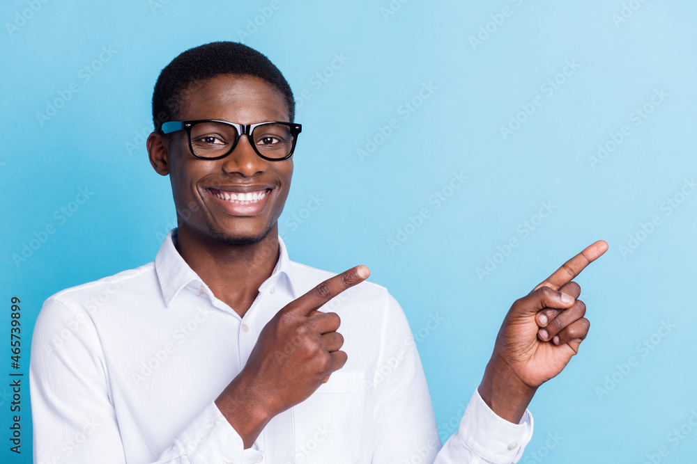 Photo of cute charming dark skin guy dressed formal shirt glasses smiling pointing empty space isolated blue color background Photo of cute charming dark skin guy dressed formal shirt glasses smiling pointing empty space isolated blue color background