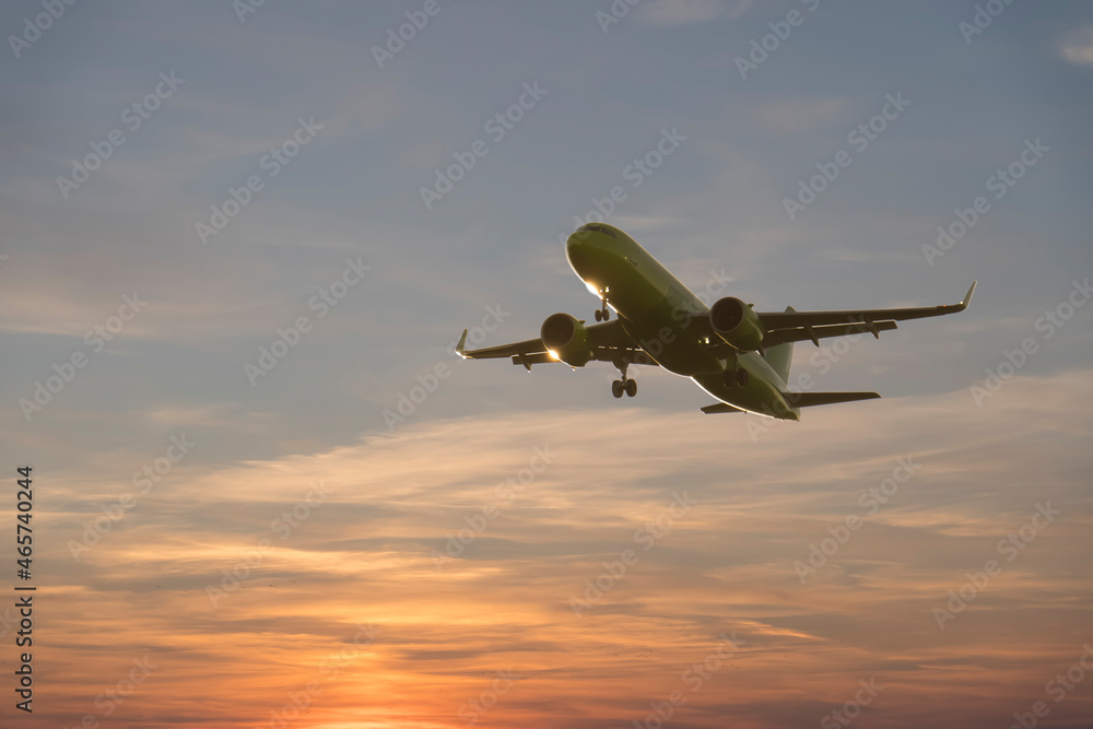 Airplane flight on the blue summer sky. Takeoff or landing of a passenger plane with traveling tourists. Air travel and travel industry concept