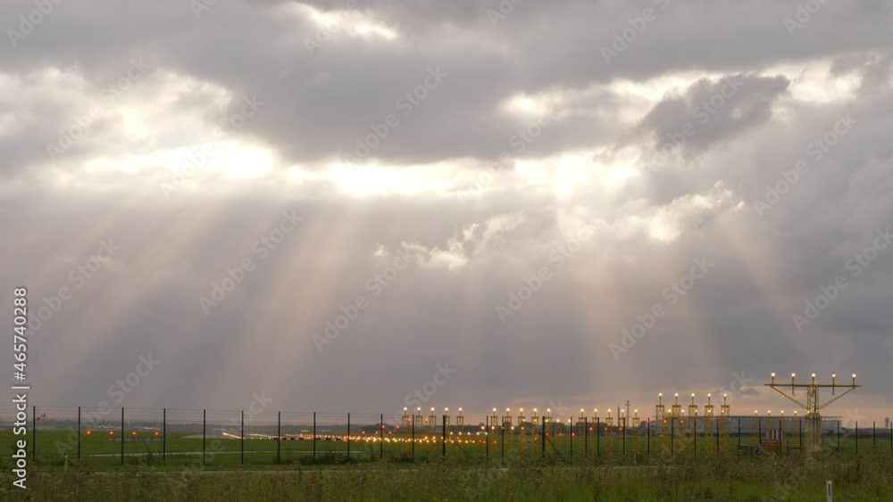 Scenic panorama, cumulus clouds and sun light beams shine over airport fields. Yellow lightbars with approaching light system at end of old runway of Amsterdam Airport Schiphol Scenic panorama, cumulus clouds and sun light beams shine over airport fields. Yellow lightbars with approaching light system at end of old runway of Amsterdam Airport Schiphol
