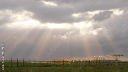 Scenic panorama, cumulus clouds and sun light beams shine over airport fields. Yellow lightbars with approaching light system at end of old runway of Amsterdam Airport Schiphol photo