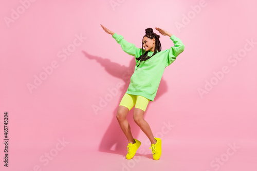 Full body photo of attractive young afro american woman dance look empty space dance isolated on pink color background