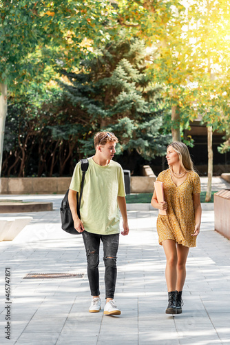 Two young university students, a man and a woman, walking around campus and talking about their studies