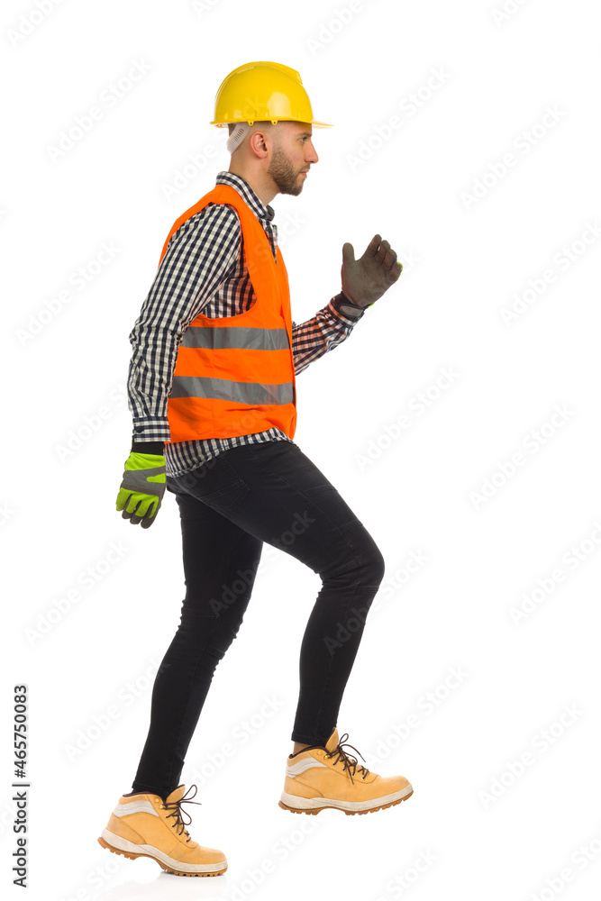 Construction worker is going up the stairs. Side view. Studio shot isolated. Construction worker is going up the stairs. Side view. Studio shot isolated.
