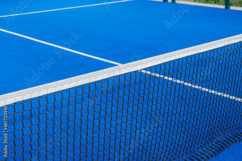 Net and serving lines of a blue paddle tennis court © Vic