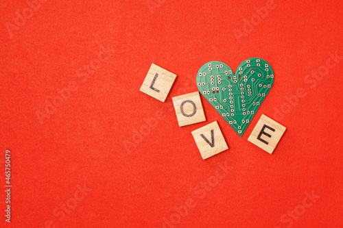 Circuit board in the shape of heart with text love on red background. Valentine's Day concept photo.