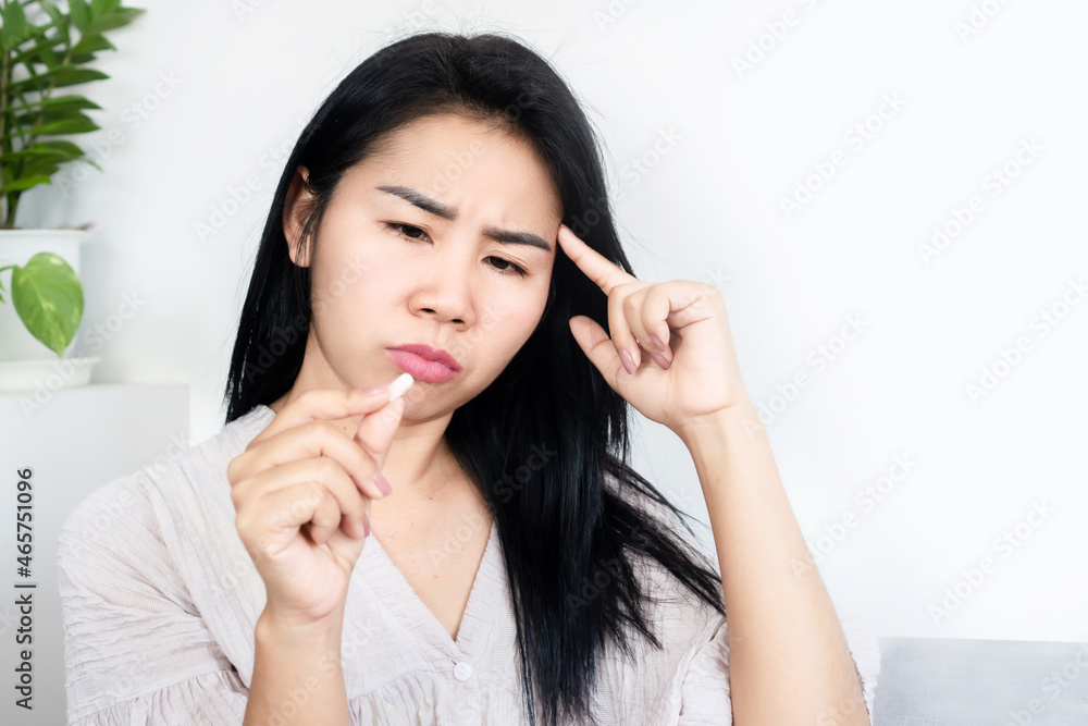 Asian woman forget to take medicine hand holding pill loss memory, thinking and confused something Asian woman forget to take medicine hand holding pill loss memory, thinking and confused something
