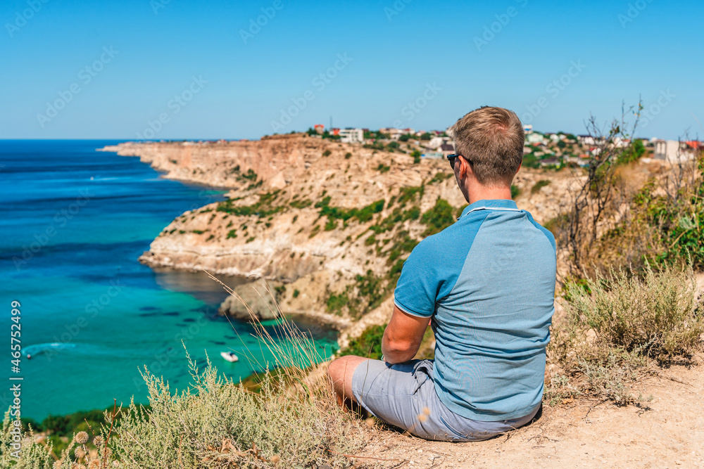 A young man travels to Cape Fiolent, the most famous place in the Crimea with an azure wave and rocks