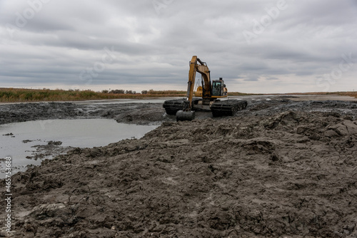 Amphibious water excavator clears the dried river bed channel from the bed silt