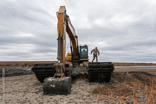 Amphibious water excavator clears the dried river bed channel from the bed silt