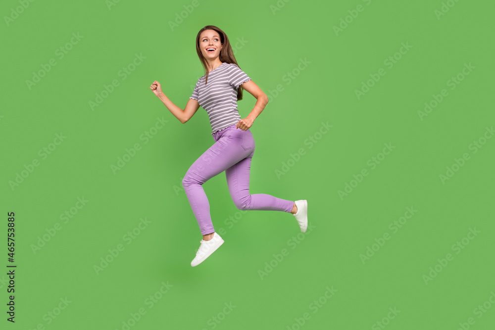 Full length body size view of attractive cheerful motivated girl jumping running isolated over bright green color background Full length body size view of attractive cheerful motivated girl jumping running isolated over bright green color background