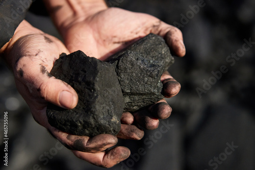 poor middle-aged man holding the hands of stone coal for sale to provide food for his family