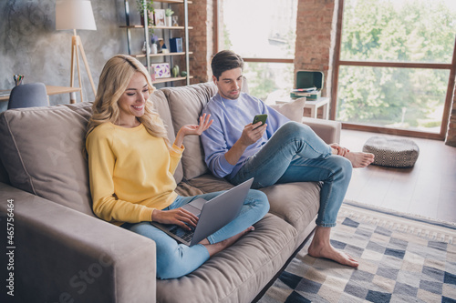 Portrait of attractive cheerful couple using gadget laptop watching video pastime at home loft industrial interior indoors
