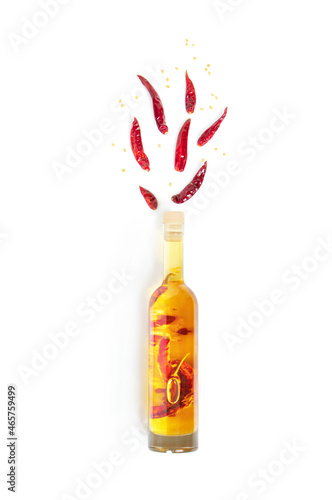 Creative flat lay bottle of natural cooking spicy oil and dried hot chili pepper on white background. Source of monounsaturated fats. Concept of healthy plant food. Top view, layout.