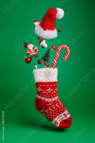 Creative layout made with flying Christmas socks, Santa Claus, pine tree and candy cane on green background. Minimal New Year season concept. Winter holidays idea.