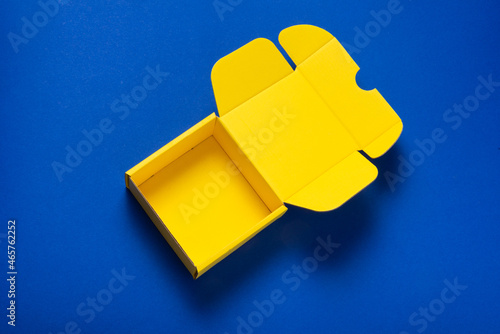 Simple yellow cardboard box on color background, empt inside, opened