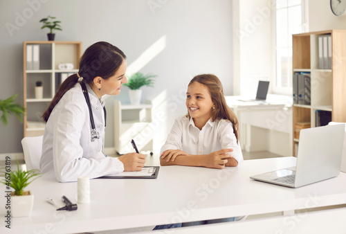 Smiling teen girl child speak talk with female doctor at consultation in clinic. Caring woman pediatrician checkup consult happy little kid patient in hospital. Good medical service  healthcare.