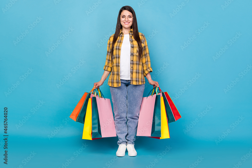 Full length body size view of attractive cheerful girl holding new things buyings isolated over bright blue color background Full length body size view of attractive cheerful girl holding new things buyings isolated over bright blue color background