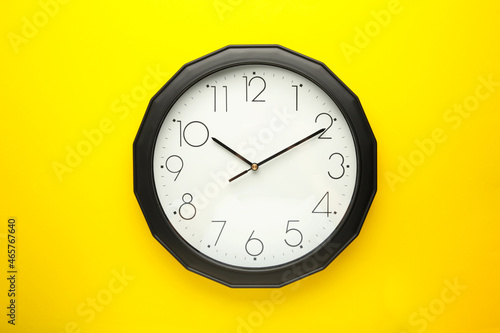 Black wall clock on the yellow background.