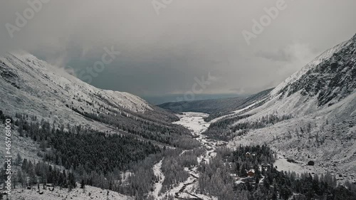 The foot of the glacier of the huge Belukha mountain, the valley of the Aktru River, the Altai mountains. Cloudy weather, storm, wildlife, winter forest, frozen mountain river in the valley of the