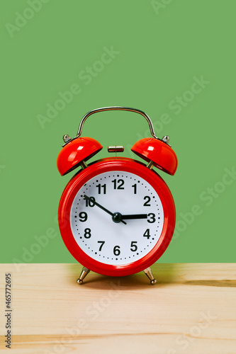 traditional red alarm clock on a green background