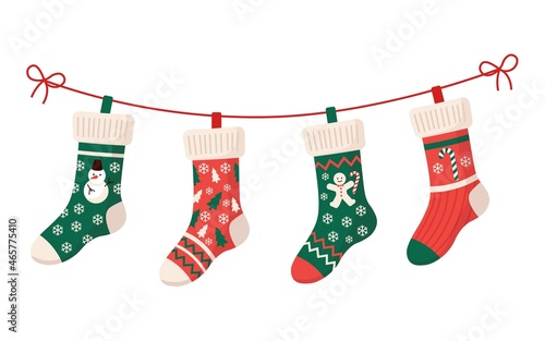 Christmas stockings with various traditional colorful holiday ornaments. Hanging children clothing elements with cute xmas patterns on rope. Red, green socks with snowflakes, snowman, christmas tree. 