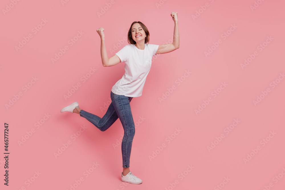 Portrait of dreamy inspired champion lady raise fists astonished mood on pink background Portrait of dreamy inspired champion lady raise fists astonished mood on pink background