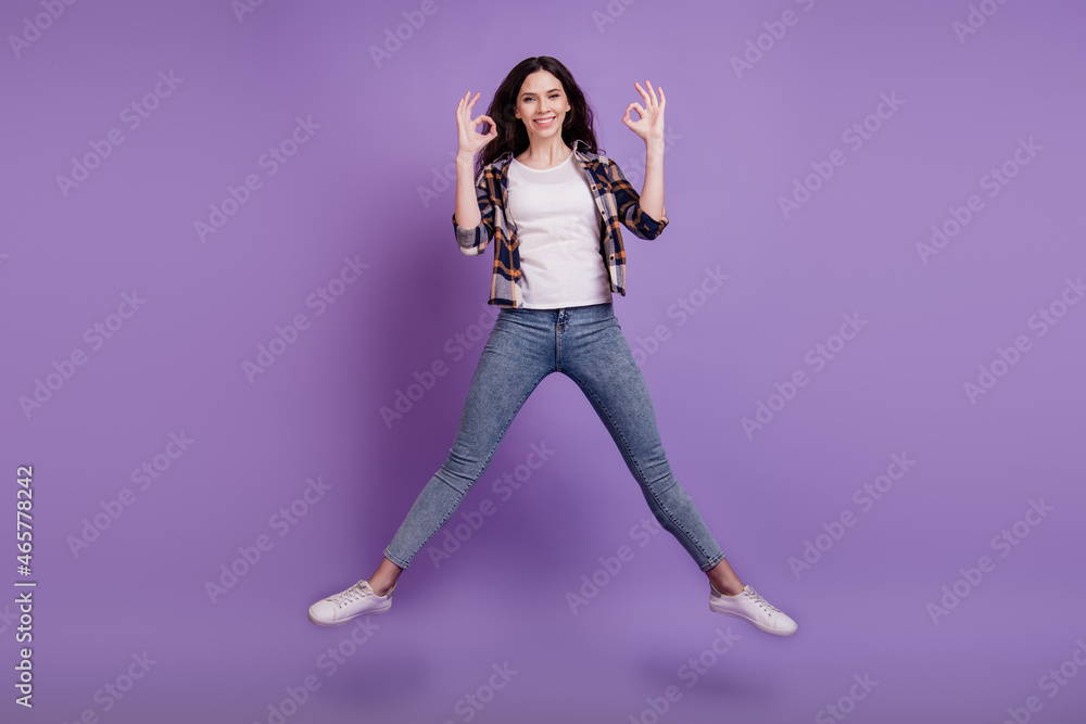 Full size photo of young attractive girl happy positive smile jump up show okay alright sign isolated over violet color background