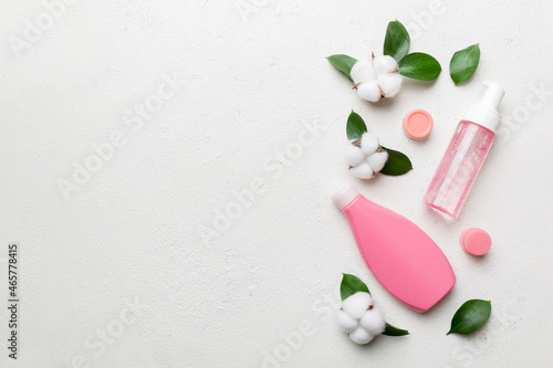 Organic cosmetic products with cotton flower and green leaves on cement background. Copy space, flat lay