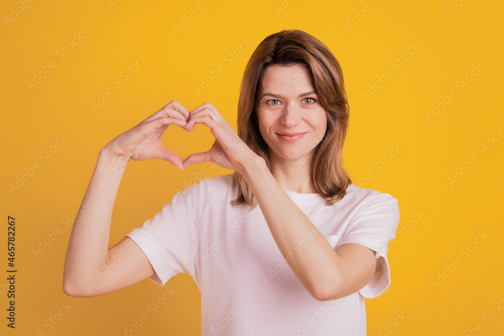 Photo of affectionate lady fingers demonstrate heart shape symbol wear casual t-shirt on yellow background Photo of affectionate lady fingers demonstrate heart shape symbol wear casual t-shirt on yellow background
