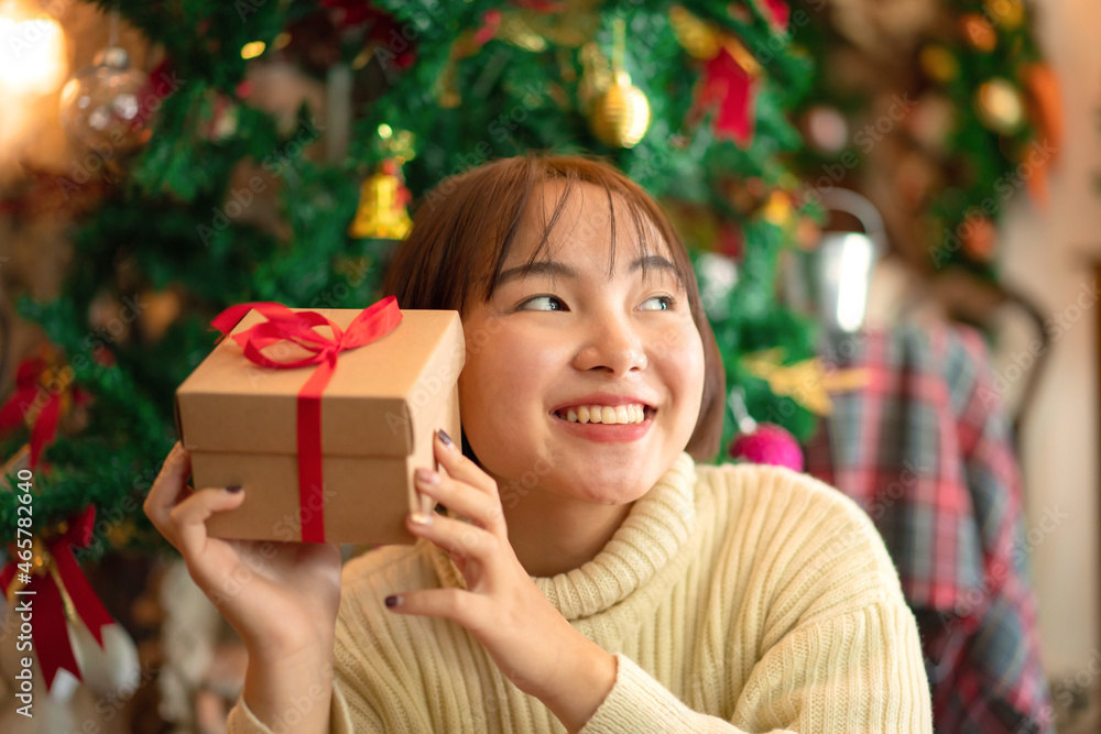 Happy beautiful woman is holding up a present box with smile in celebration christmas or new year