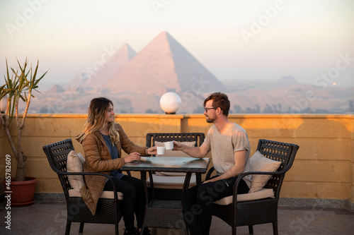 young couple having breakfast with view of ancient pyramids in Egypt