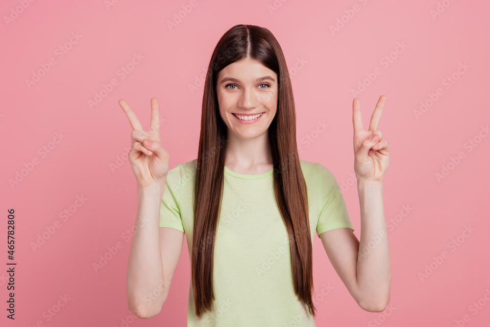 Photo of young cheerful girl happy positive smile show peace cool v-sign isolated on pink color background Photo of young cheerful girl happy positive smile show peace cool v-sign isolated on pink color background