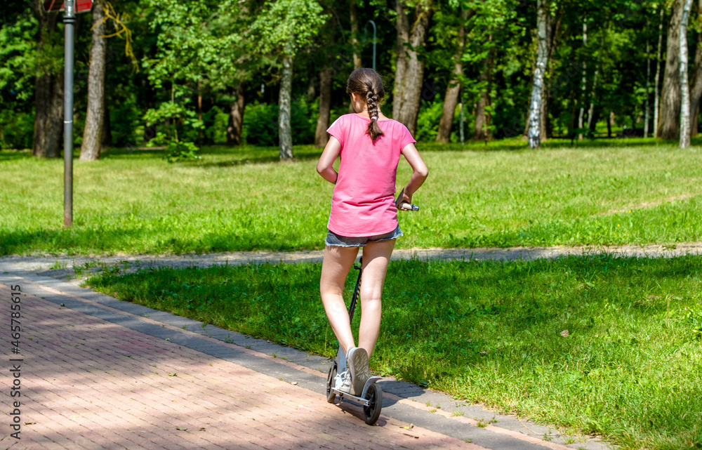 A girl rides a scooter in a city Park
