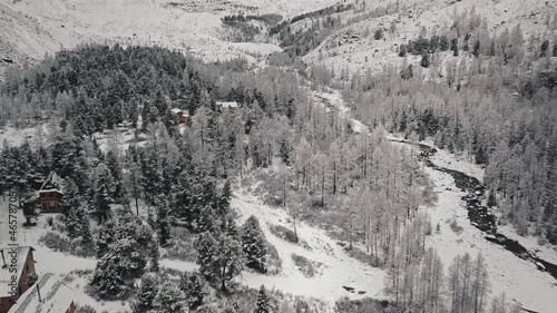 A huge Belukha Mountain, the valley of the Aktru River, the Altai Mountains, the foot of glaciers, a small village and treetops. Winter forest, frozen mountain river in the valley of the Chuya and