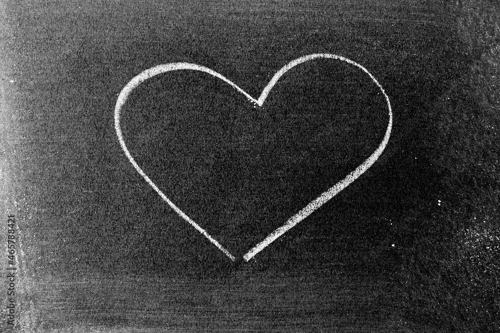 White color chalk hand drawing in heart shape on blackboard or chalkboard background White color chalk hand drawing in heart shape on blackboard or chalkboard background