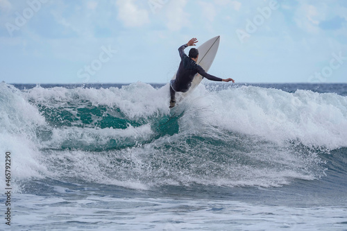 surfer doing an acrobatic stunt on the crest of the wave