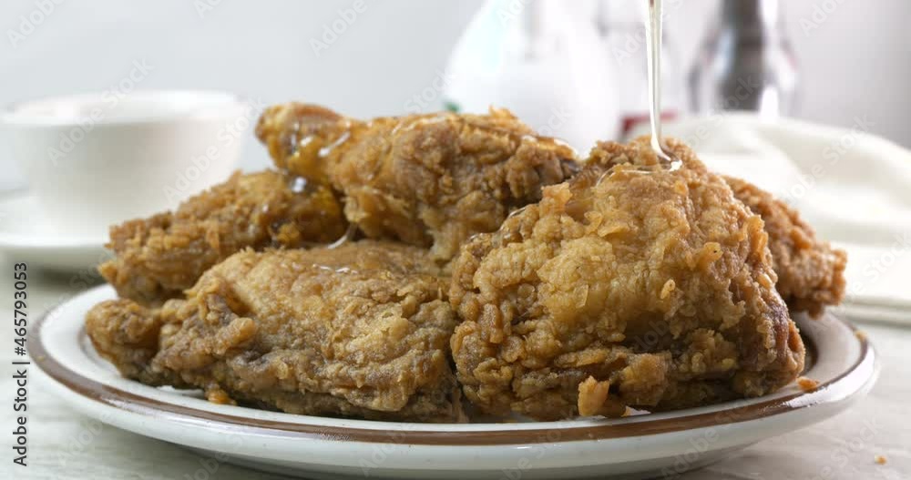 Drizzling honey onto breaded fried chicken close up Drizzling honey onto breaded fried chicken close up